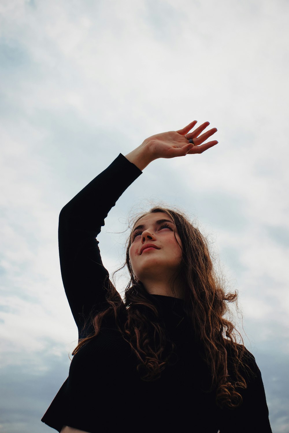 woman in black long sleeve shirt raising her right hand