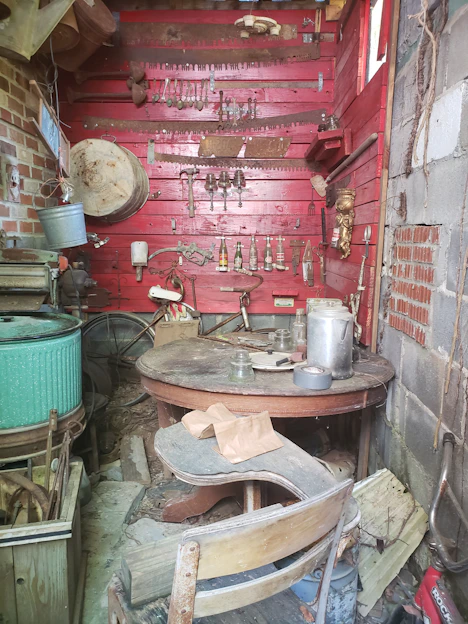 A rustic workshop corner filled with vintage scrap materials and partially assembled art pieces.