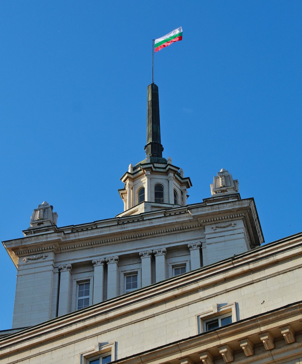 white concrete building with flag on top under blue sky during daytime