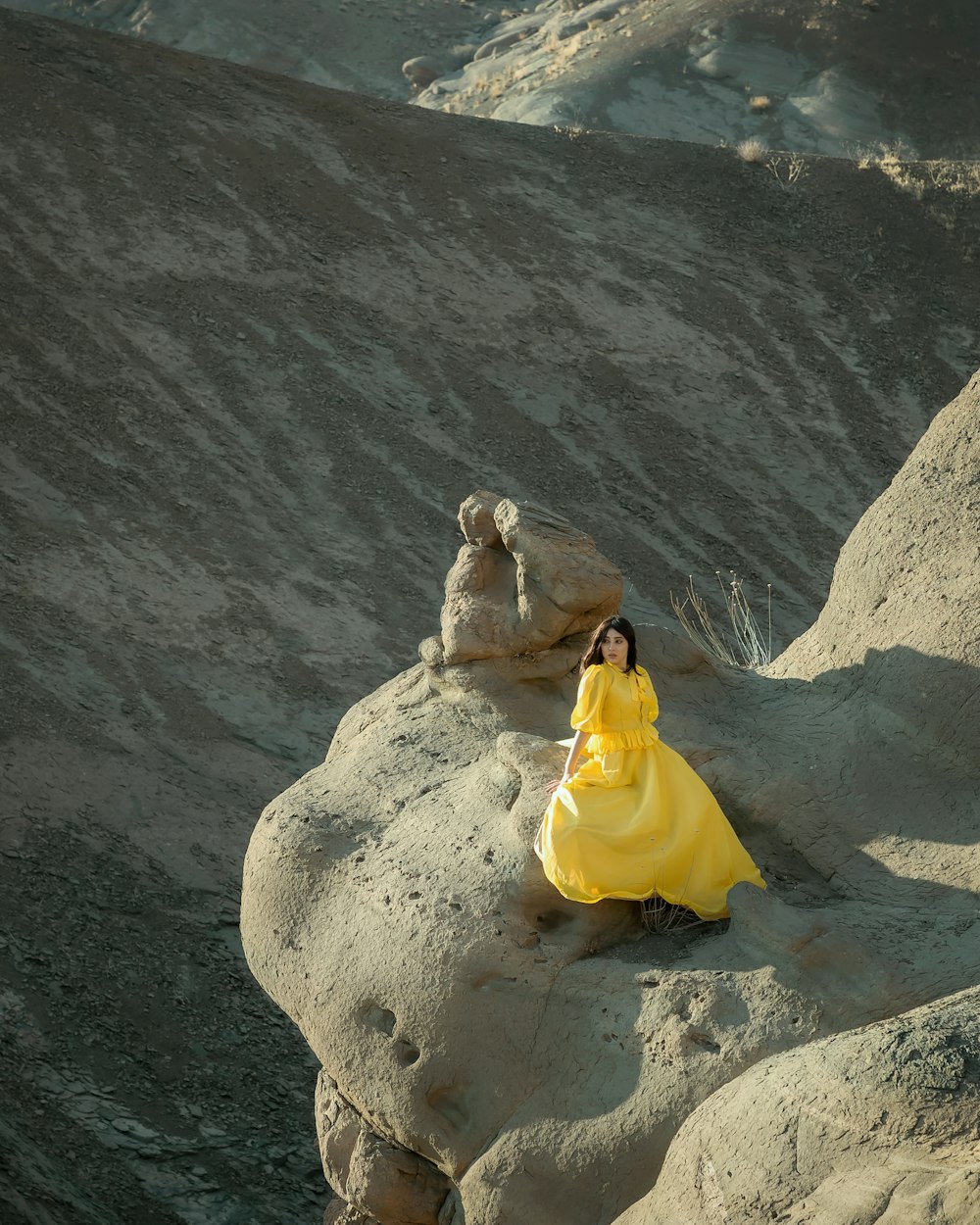 woman in yellow dress sitting on rock formation
