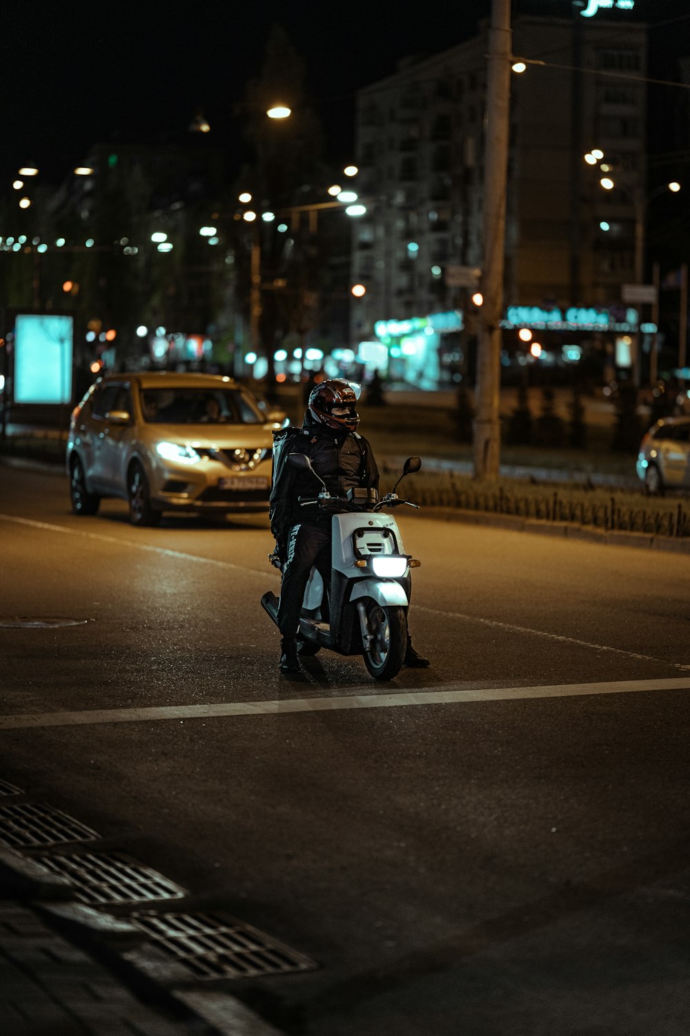 person riding white and black motorcycle on road during night time