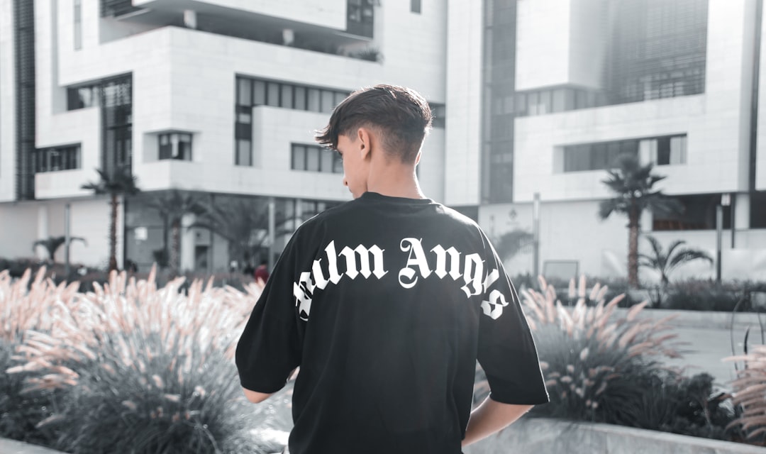 man in black and white crew neck t-shirt standing near pink flowers during daytime