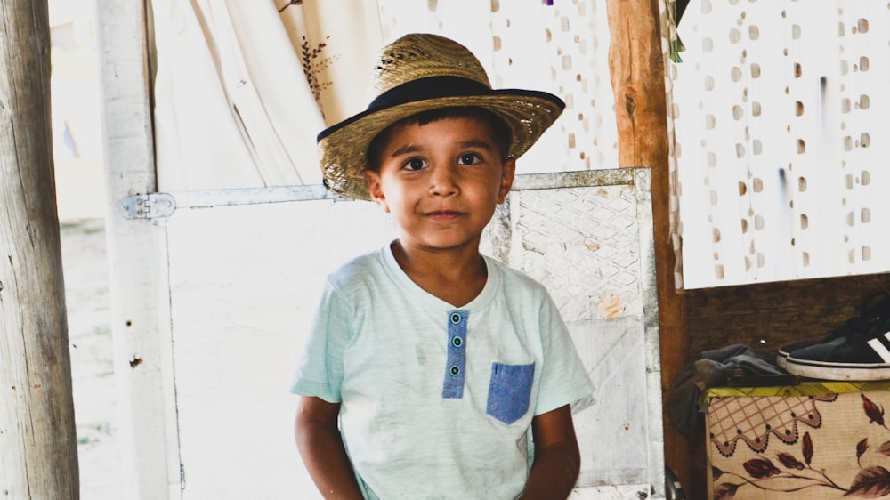 boy in white crew neck t-shirt wearing brown straw hat