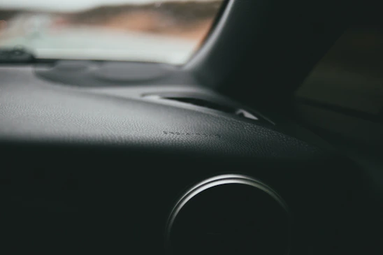 Close-up of a shiny black car dashboard made from ABS plastic.