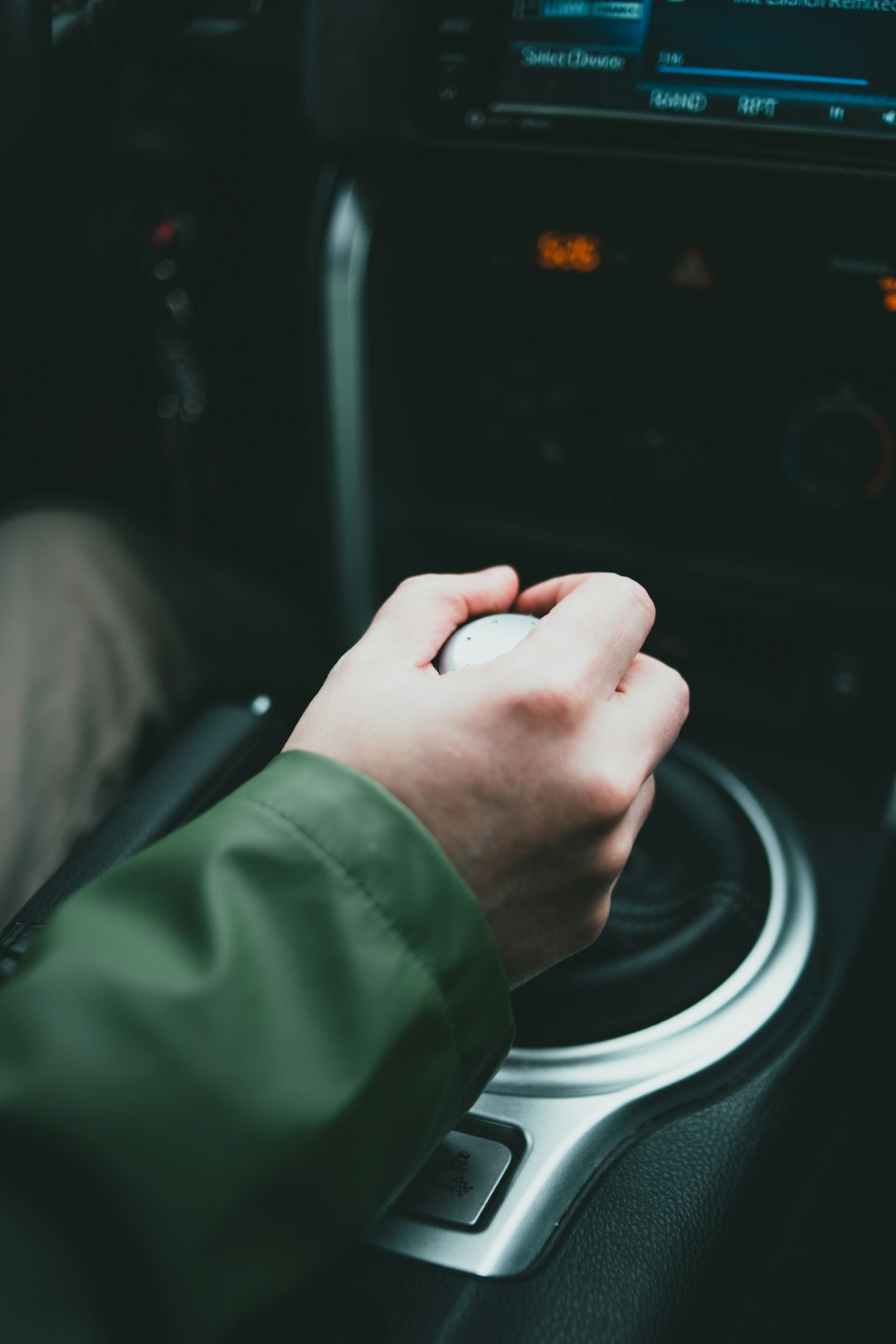 person in green long sleeve shirt holding car steering wheel