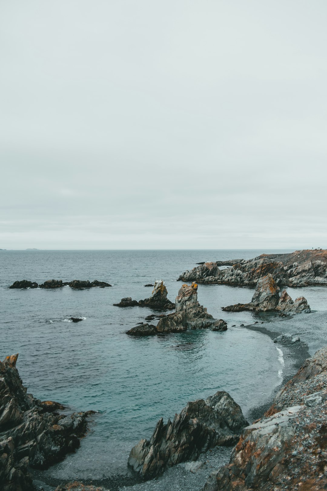 brown rock formation on sea under white clouds during daytime