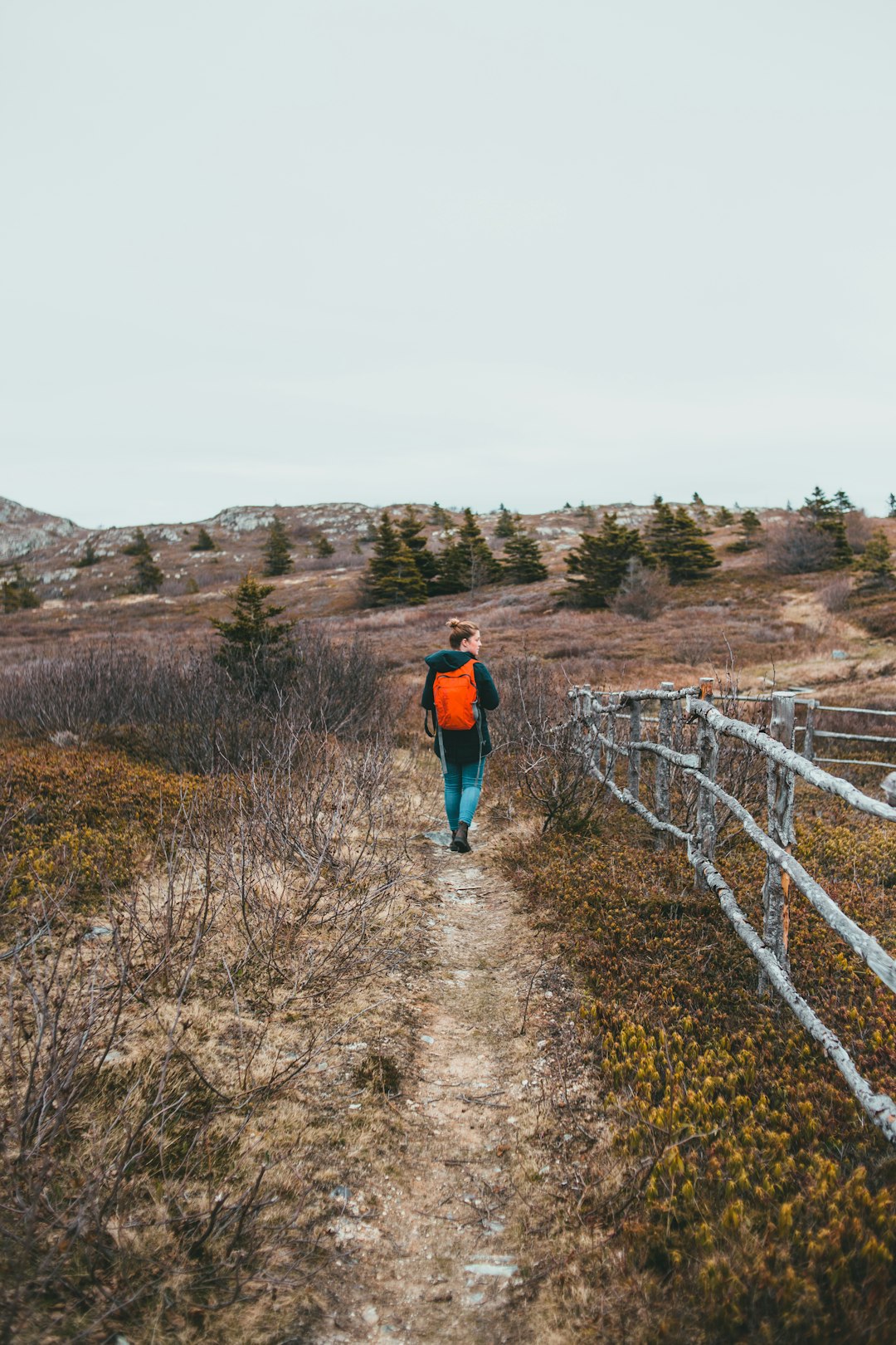 man in red jacket walking on dirt road during daytime