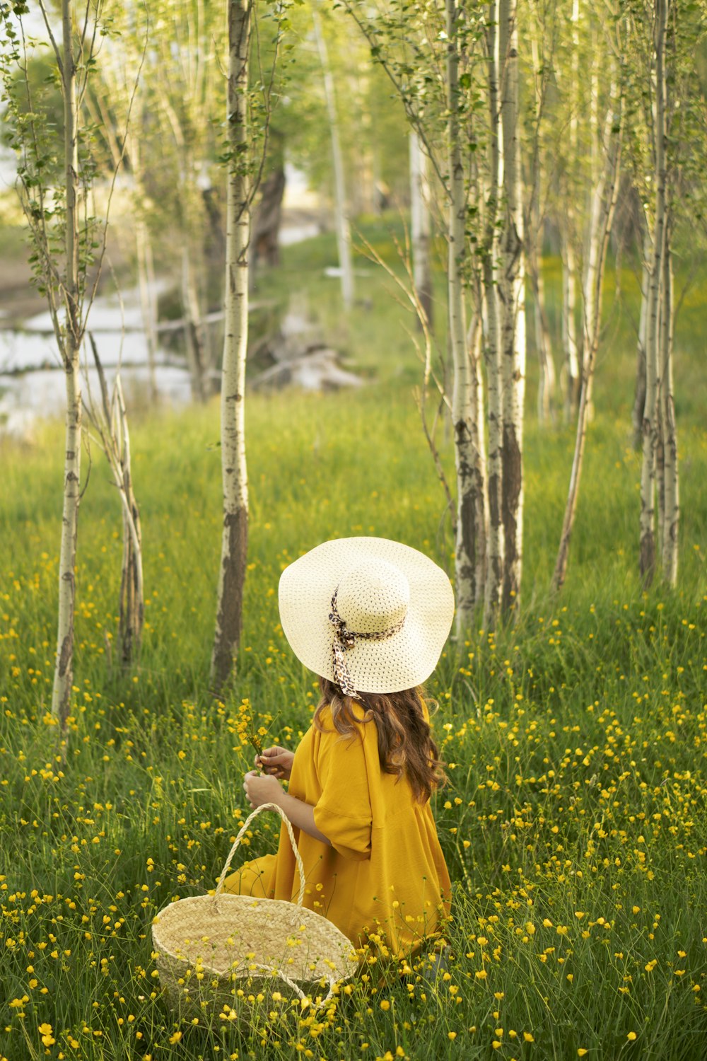 woman in yellow jacket wearing white sun hat standing on green grass field during daytime