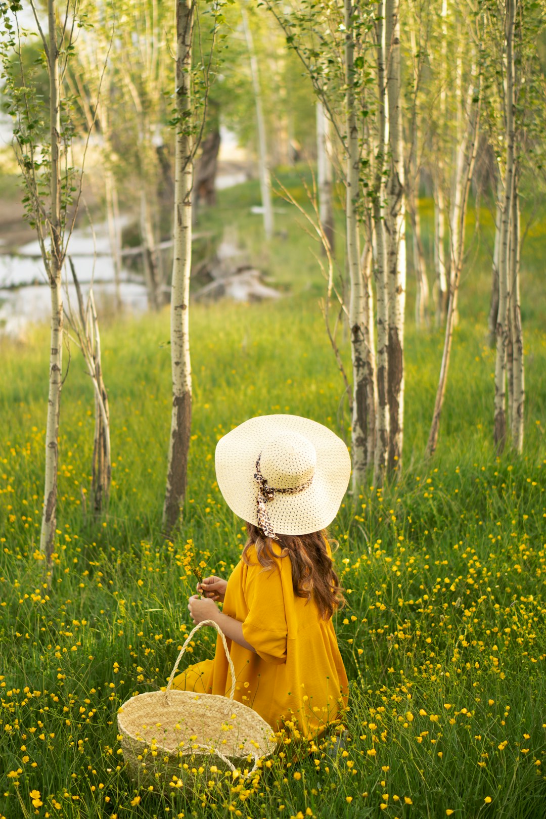 woman in yellow jacket wearing white sun hat standing on green grass field during daytime