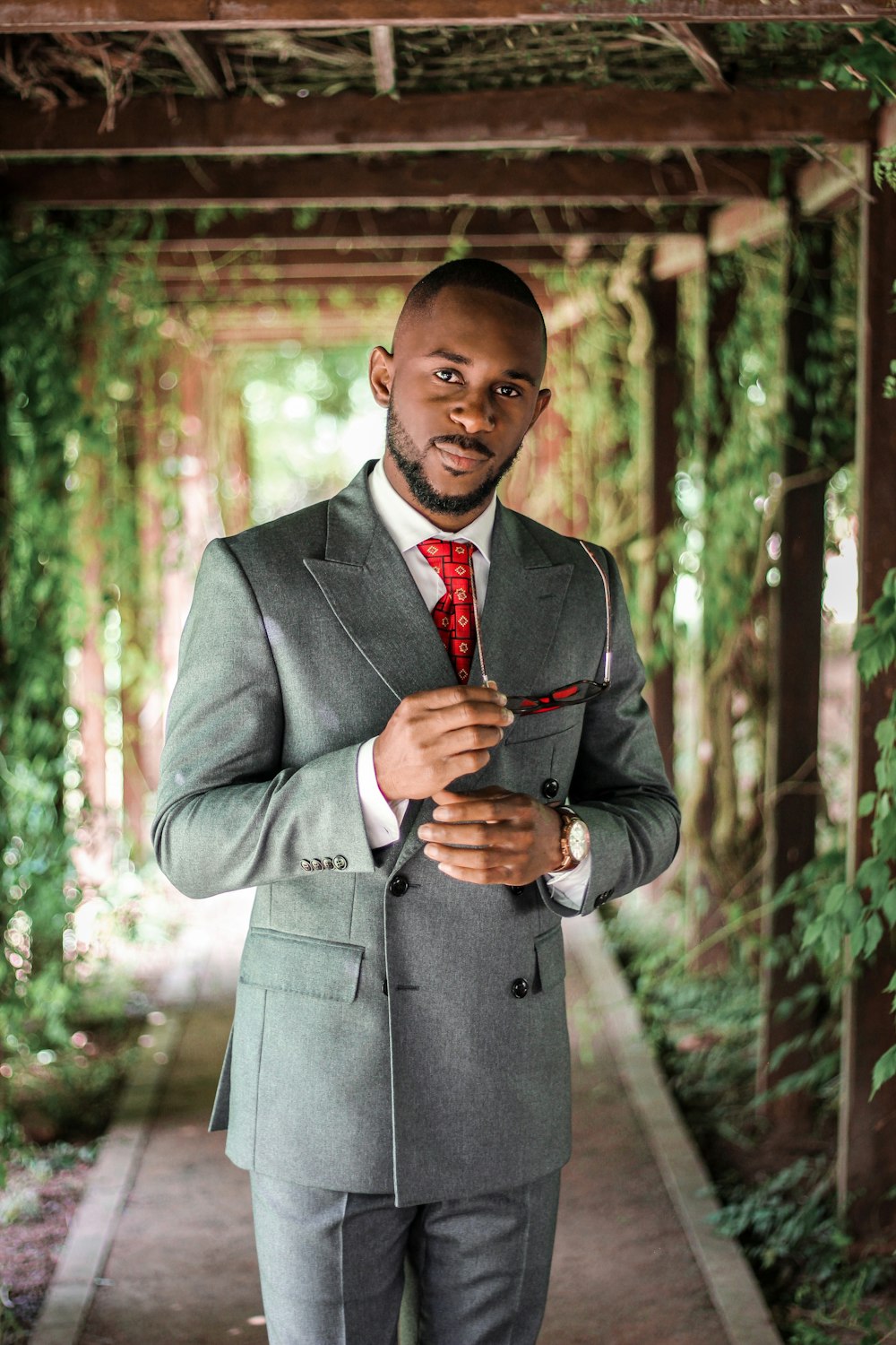 man in gray suit jacket holding red necktie