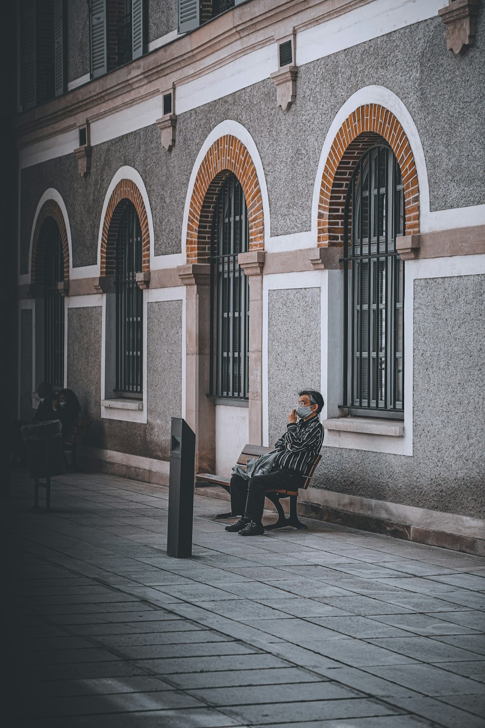 man in black jacket sitting on black bench