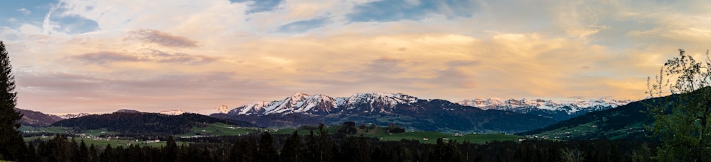 green trees and mountains under white clouds and blue sky during daytime