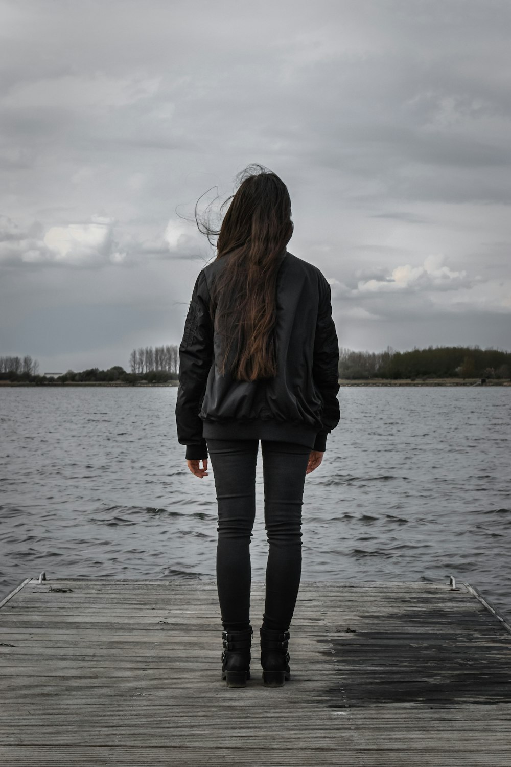 woman in black jacket standing on dock during daytime