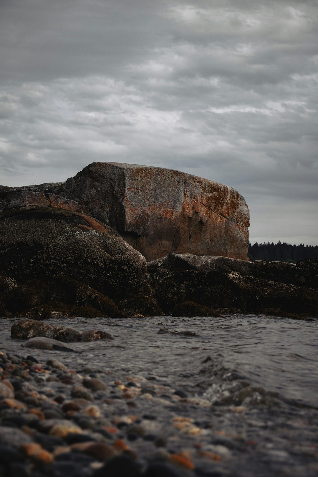 brown rock formation on body of water under cloudy sky during daytime