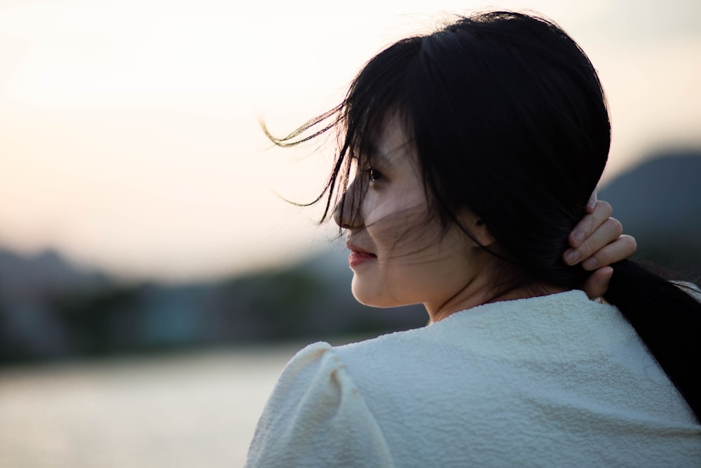 woman in white shirt looking at the sea during daytime