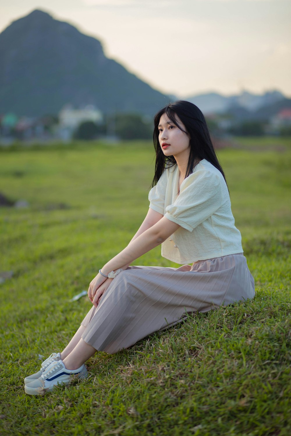 Mujer en vestido blanco sentada en el campo de hierba verde durante el día