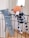 Two plush toys are hanging on a black metal railing. One toy resembles a blue elephant with a long nose, while the other is a spotted dog with an orange head. Both toys appear to be handmade and are positioned as if they are playfully hanging on the bars.