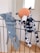 Two plush toys are hanging on a black metal railing. One toy resembles a blue elephant with a long nose, while the other is a spotted dog with an orange head. Both toys appear to be handmade and are positioned as if they are playfully hanging on the bars.