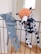 Two plush toys are hanging on a black metal railing. One toy resembles a blue elephant with a long nose, while the other is a spotted dog with an orange head. Both toys appear to be handmade and are positioned as if they are playfully hanging on the bars.