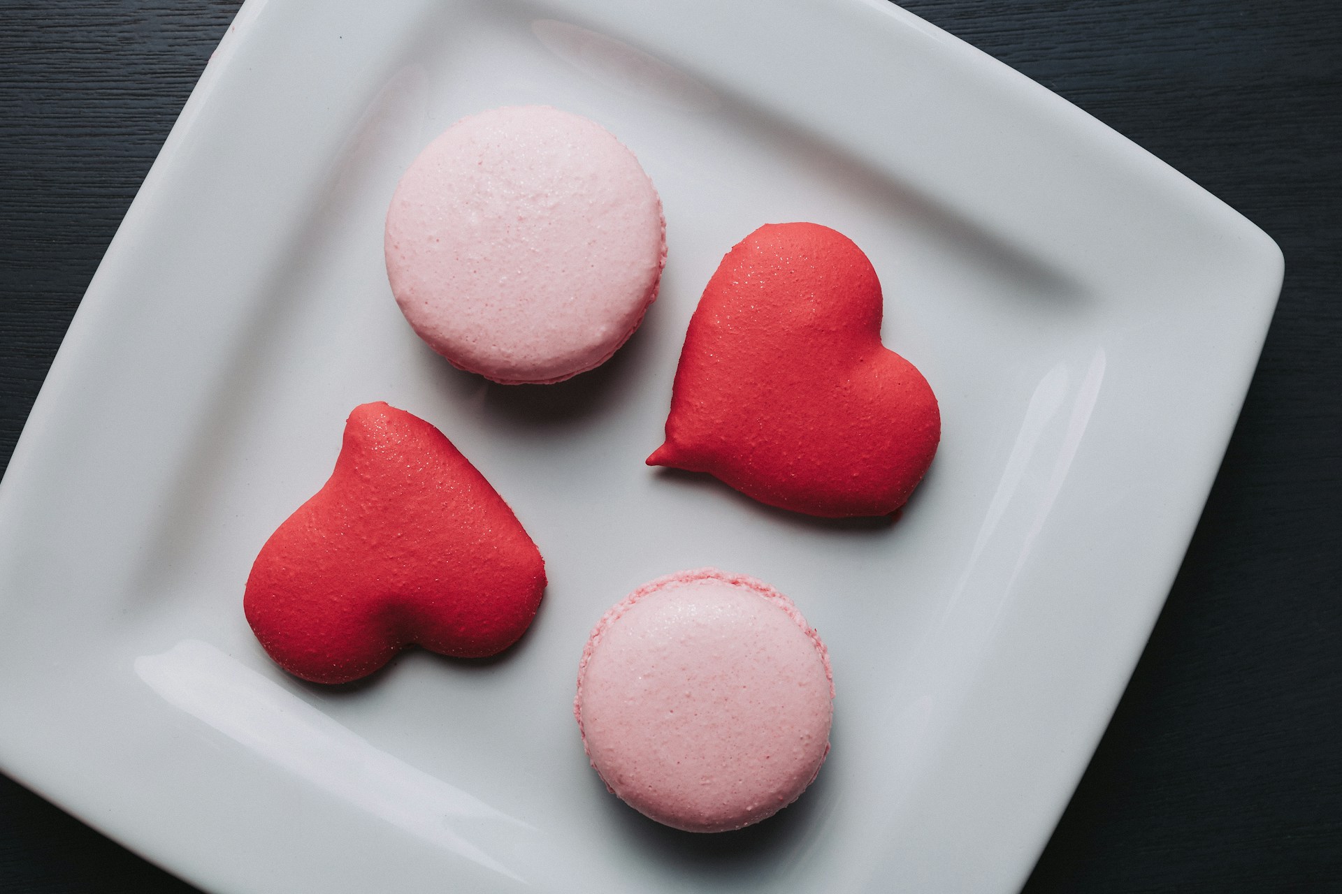 Macarons and hearts on a white plate.
