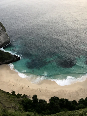 Drone view showcasing a secluded beach with crashing waves and dramatic cliffs.
