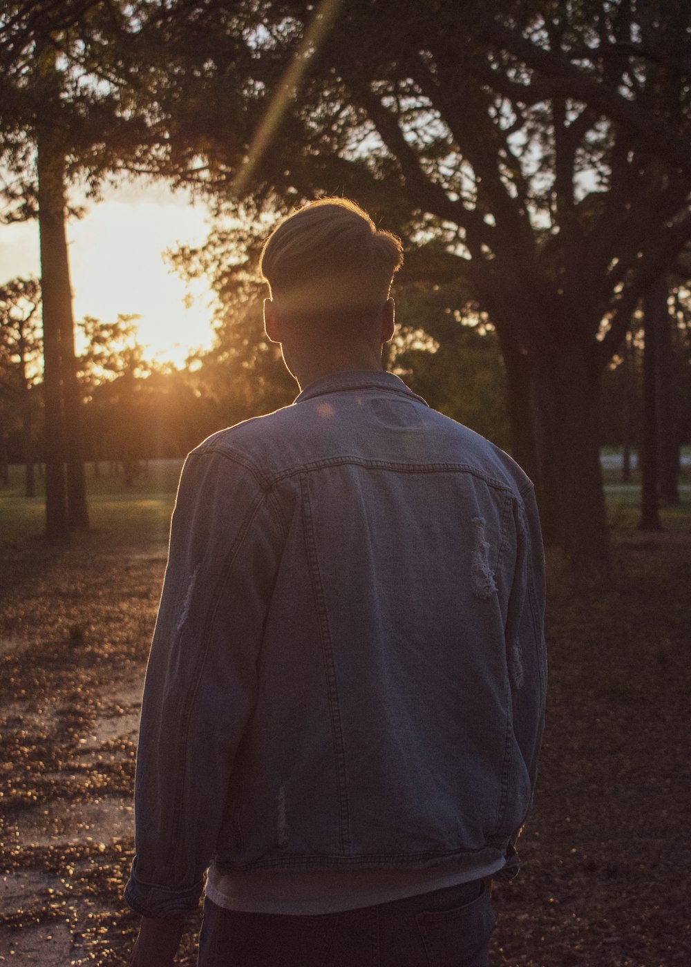 man in blue dress shirt standing near trees during daytime