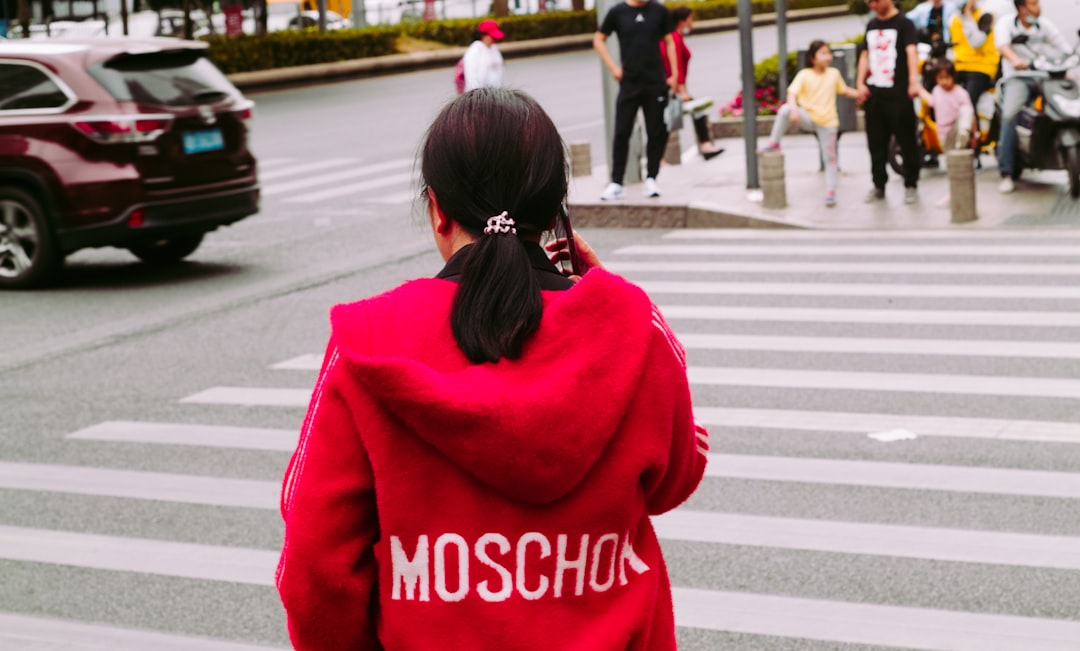 woman in red and white sweater standing on pedestrian lane during daytime