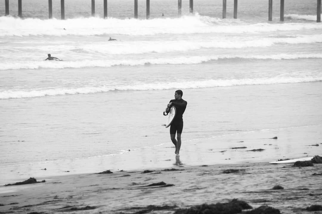 man in black wet suit walking on beach during daytime