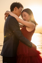man in black suit kissing woman in red dress