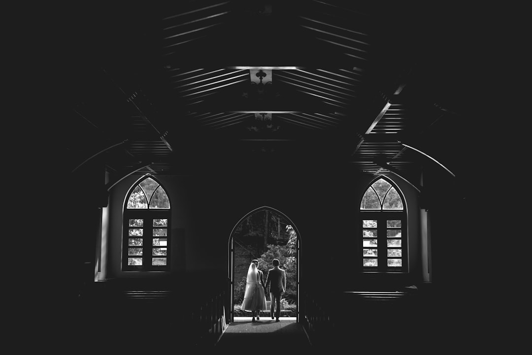 grayscale photo of couple standing in front of window