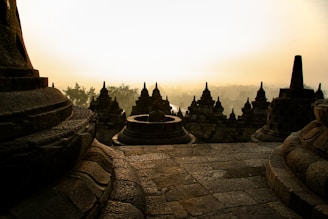 A serene view of Borobudur Temple at sunrise with soft golden light.