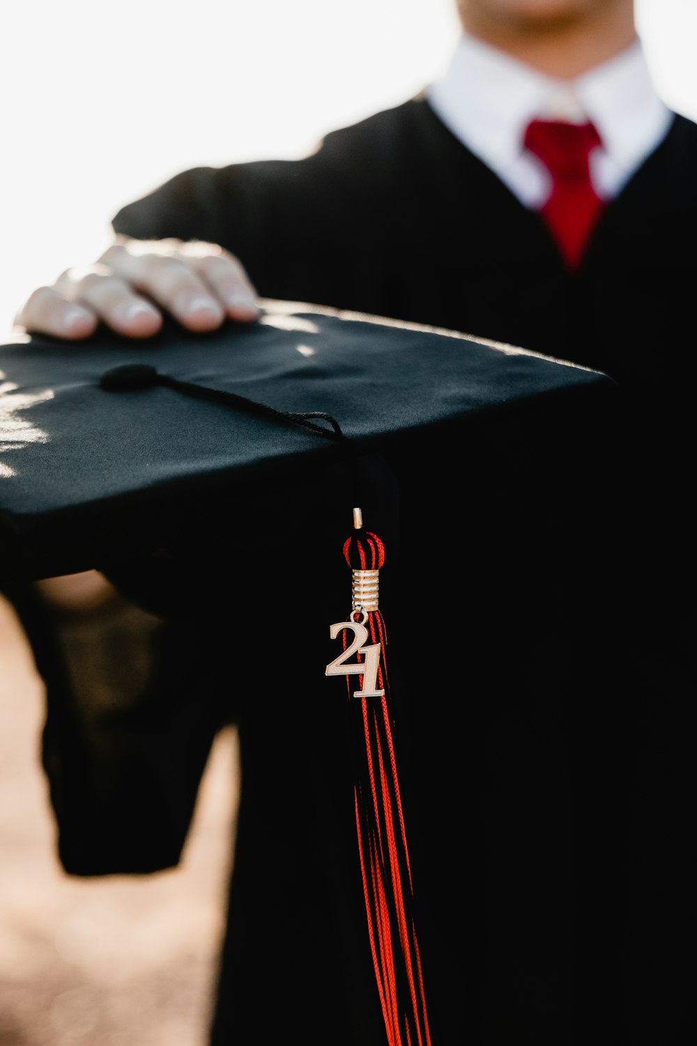 person in academic dress holding black academic hat