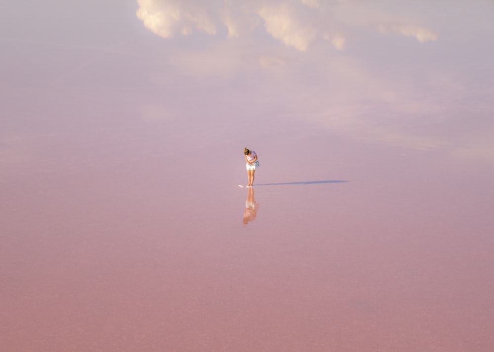 woman in white dress standing on brown sand under blue sky during daytime