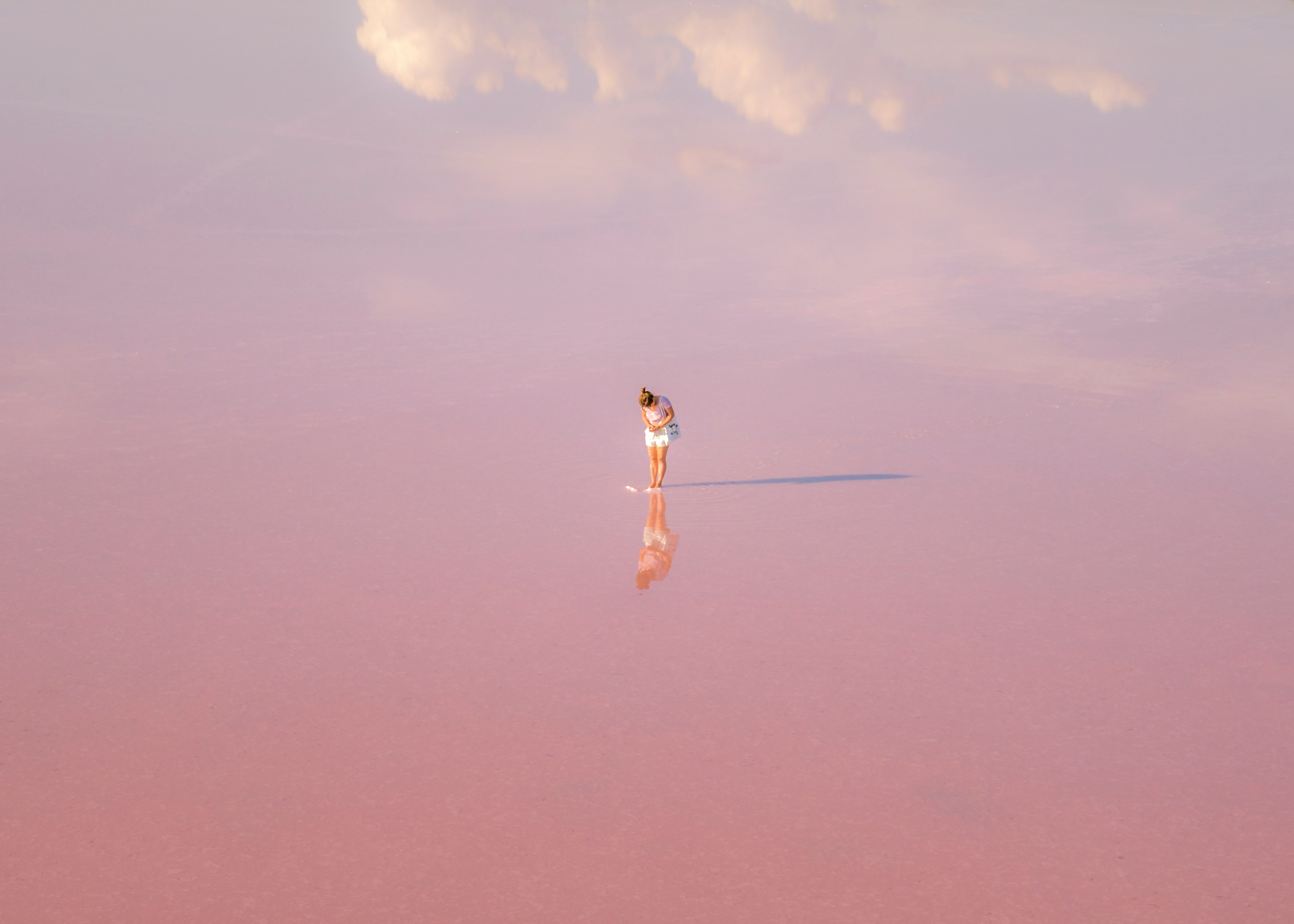 woman in white dress standing on brown sand under blue sky during daytime