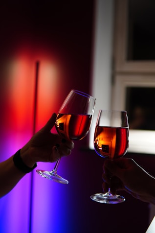 person holding clear wine glass with red liquid