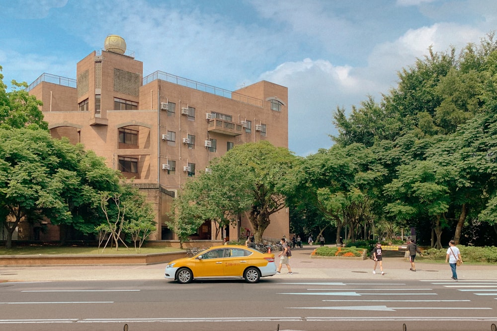 yellow sedan on road near brown concrete building during daytime