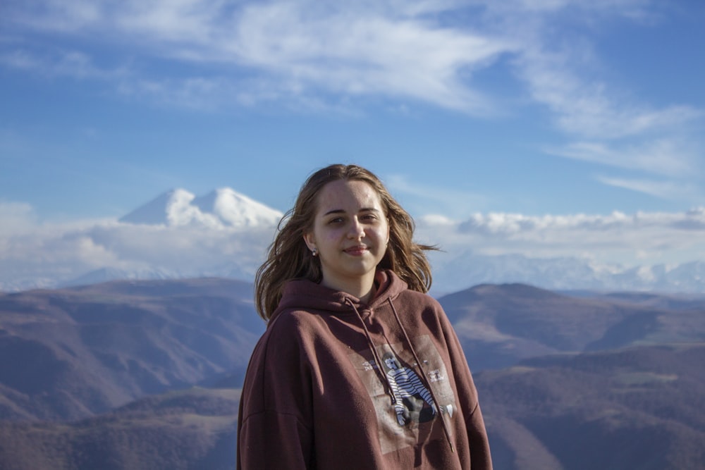 woman in red hoodie standing on top of mountain during daytime