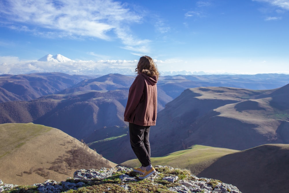 woman in brown jacket standing on rock formation during daytime