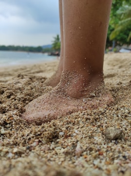Close-up of a runner's feet kicking up sand during a beach sprint start.