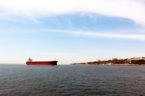 A large tanker ship loaded with refined oil products sailing near Dubai's coastline under a clear sky.