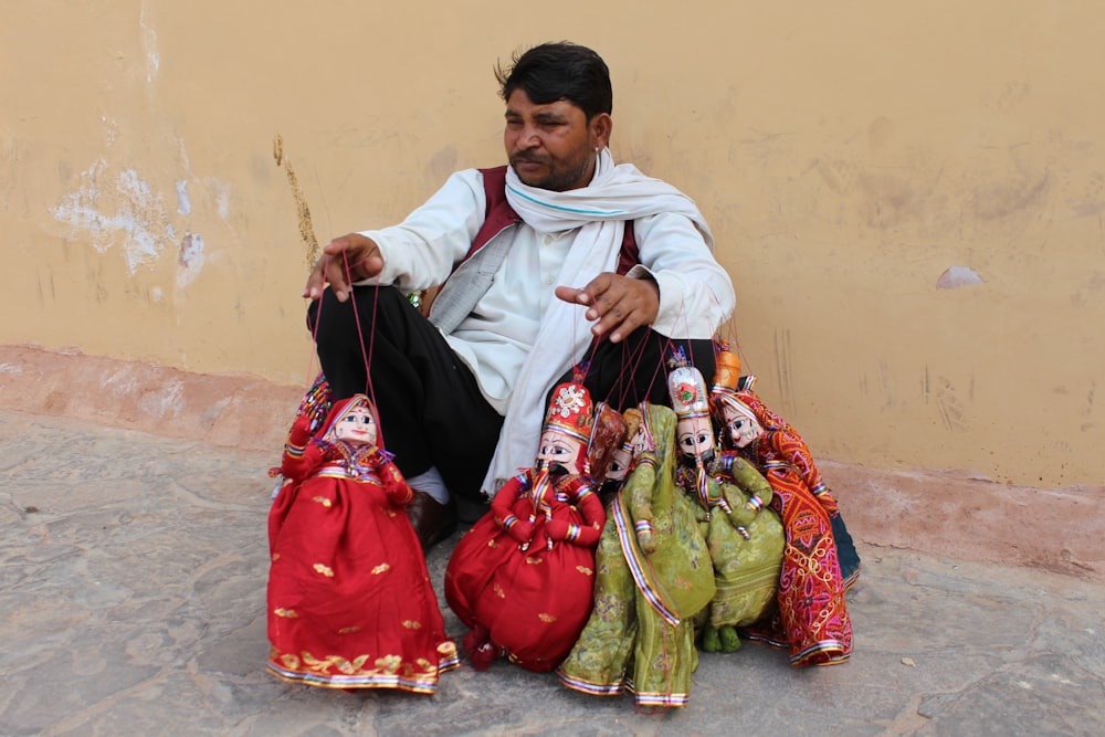 man in white thobe sitting on red and white floral textile