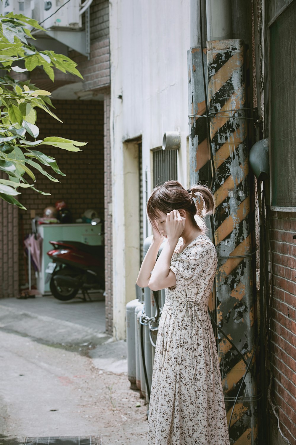 woman in brown floral dress standing near black metal gate during daytime