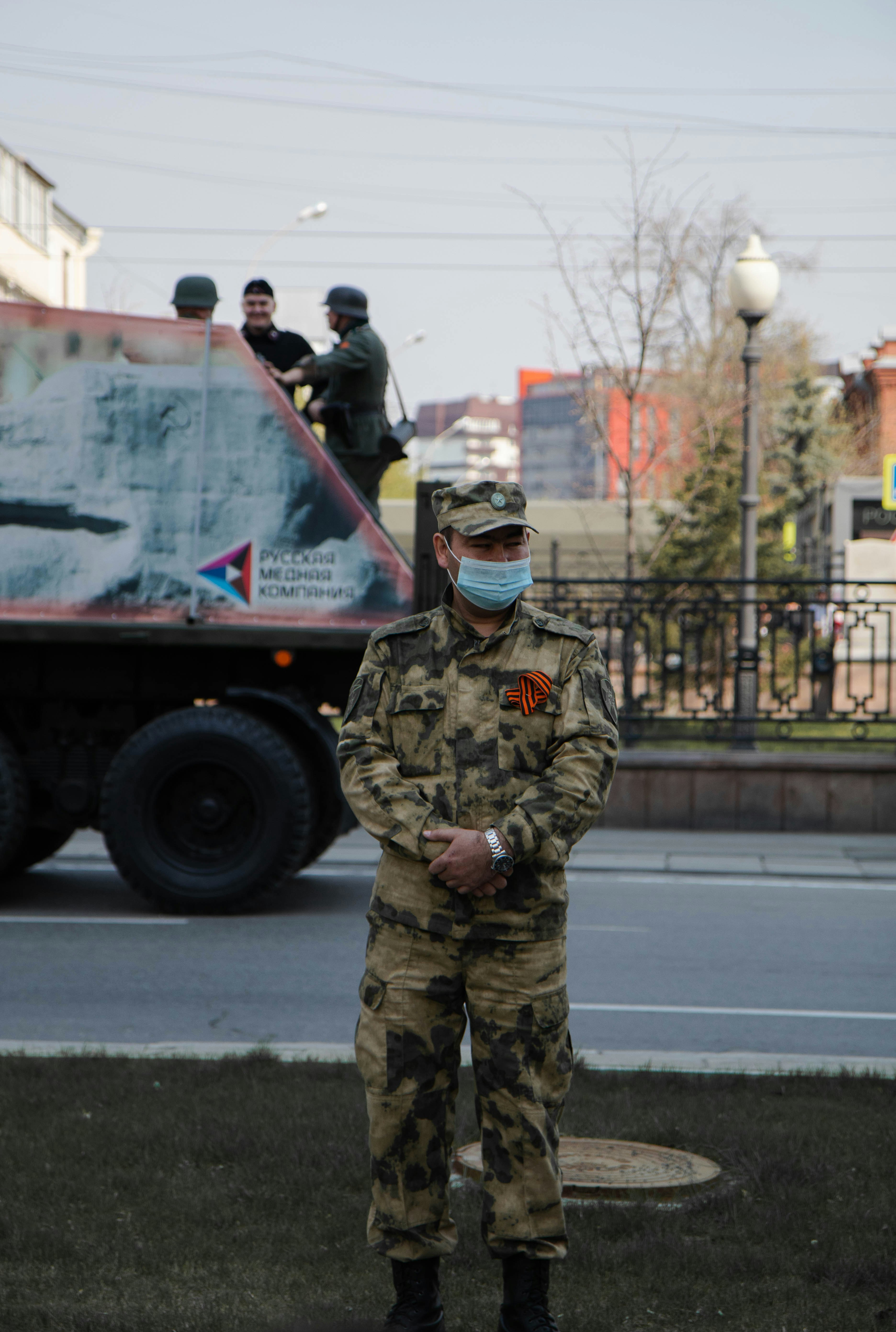 man in green and brown camouflage uniform standing on road during daytime