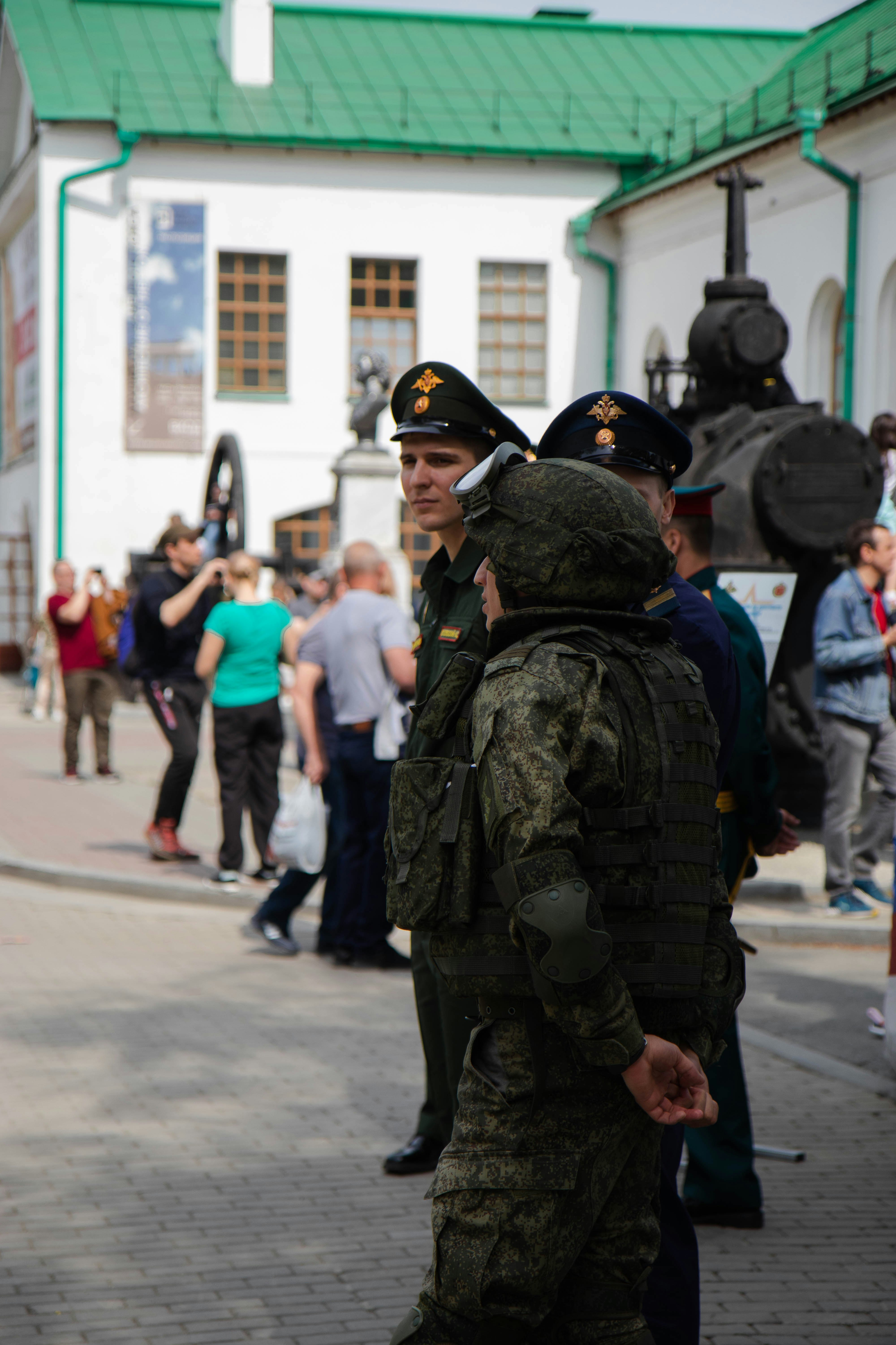 man in black and green camouflage uniform standing on street during daytime