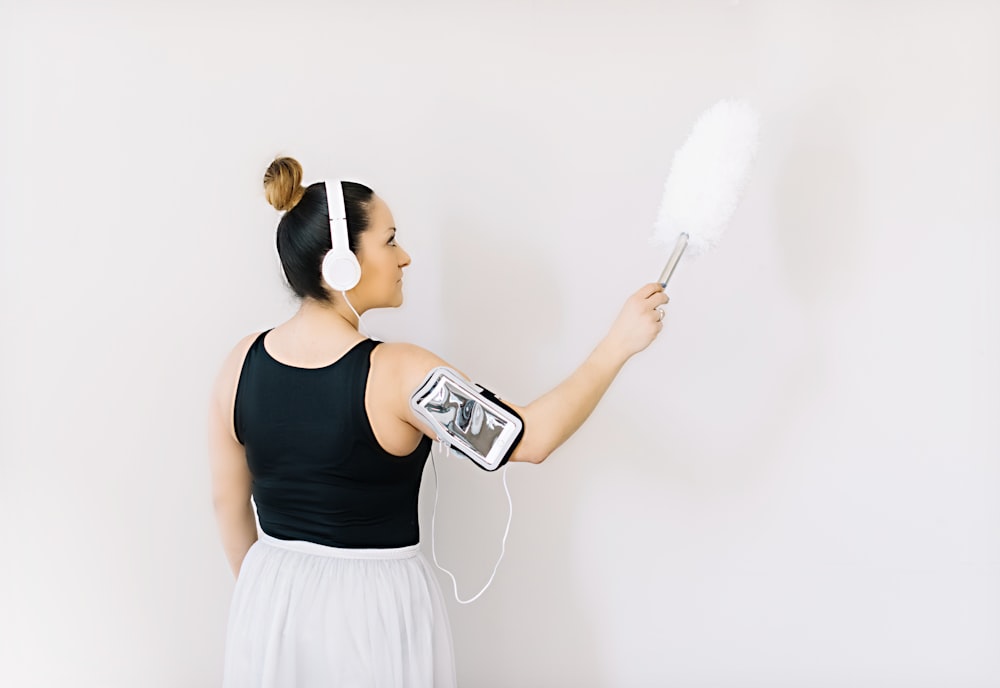 woman in black tank top and white skirt holding gray and black headphones