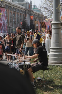 A drummer in action, surrounded by an enthusiastic crowd at an outdoor event.