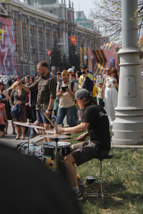 A vibrant street drummer surrounded by an enthusiastic audience in a busy Manhattan park.