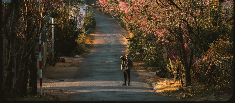 person in black jacket walking on gray asphalt road during daytime