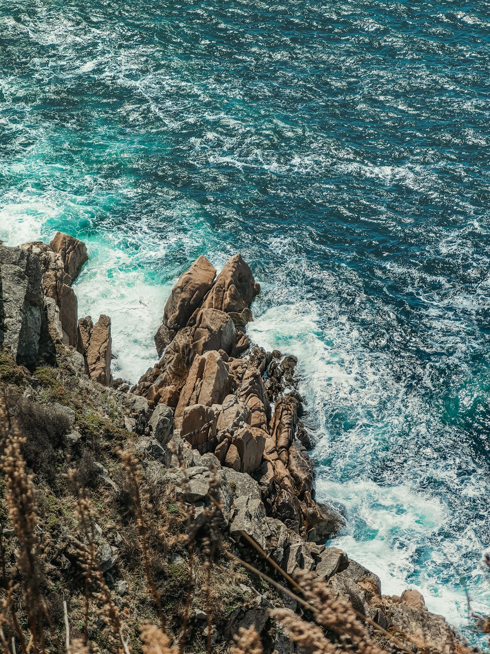 brown rocky mountain beside blue sea during daytime