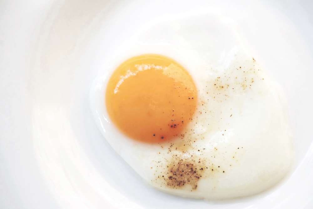 Huevo con el lado soleado hacia arriba en un plato de cerámica blanca